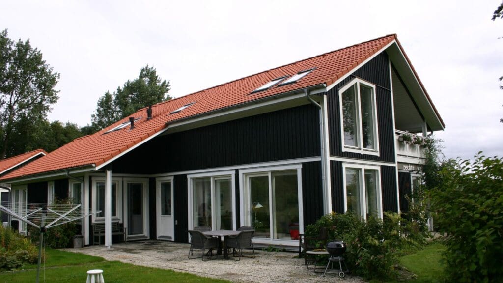 Natuurinclusieve houten schuurwoning op Terschelling met een overdekt terras en zichtbare houten draagconstructie.